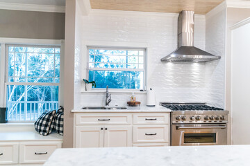 Large renovated white kitchen with textured subway tile, black iron lights and pine hardwood flooring