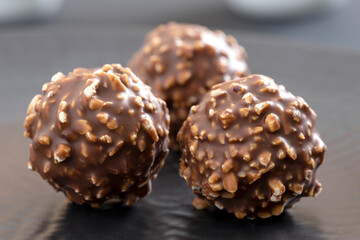 FINE ROUND CHOCOLATES WITH CHOPPED HAZELNUTS.