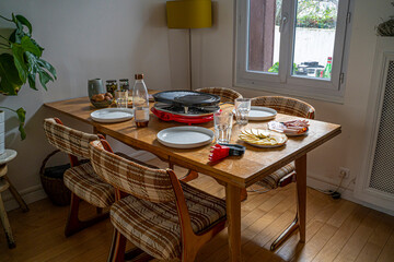 Detail photograph of a French raclette with all the typical ingredients, varieties of French cheeses, boiled potatoes, carrots, mushrooms, mushrooms, cucumbers and sausages, under natural light 