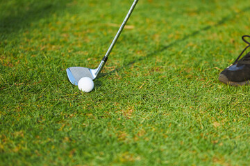 Golf clubs and golf ball on a green lawn in course. Golfers prepare to hit the ball for competition.