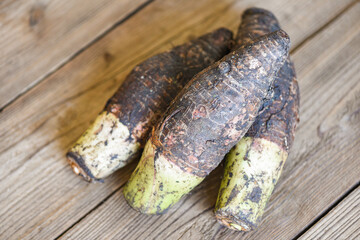 Taro root ready to cook, Raw organic brown taro on wooden table.