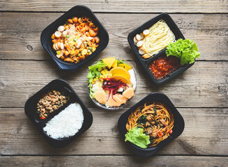 Service food order online delivery Spaghetti italian pasta macaroni cheese with sausage rice and fruit on food box, food delivery in take away boxes package on wooden table at home