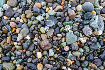 Colorful smooth rocks on the beach covered in water.