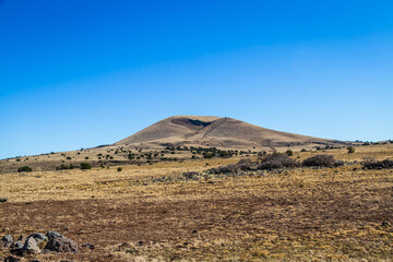 An extinct cinder cone in the distance under clear blue skies.