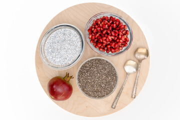 Obraz na płótnie Canvas Chia seed pudding with pomegranate seeds close up on wooden board on white background, flat lay with copy space