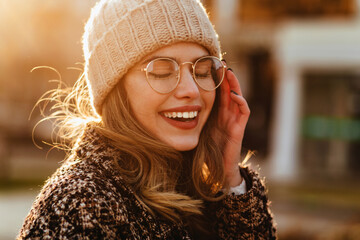 Close-up shot of happy caucasian woman in warm hat. Outdoor photo of inspired lady smiling in autumn day.