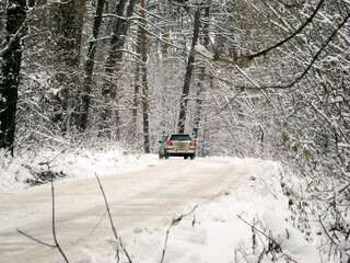 White passenger car on the snow serpentine road in the forest. On how the car color potentially...