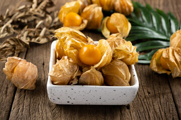 Cape Gooseberry in a white cup rests on an old wood floor