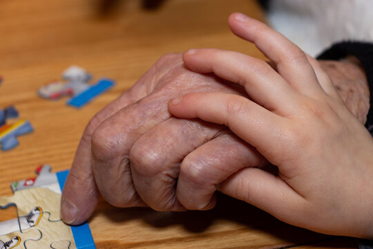 Mains unies d'un enfant et d'une personne âgée autour d'un puzzle Stock  Photo | Adobe Stock
