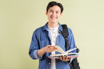 Photo of handsome Asian student smiling and holding book in hand