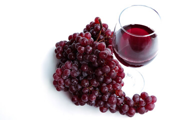 Glasses of red wine and grapes on white background