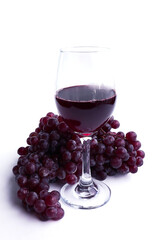 Glasses of red wine and grapes on white background