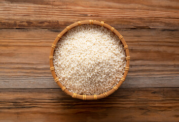 Glutinous rice in a bamboo colander set against a wooden background