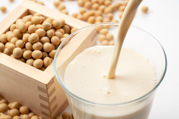 Pour soy milk into a glass placed on a white background