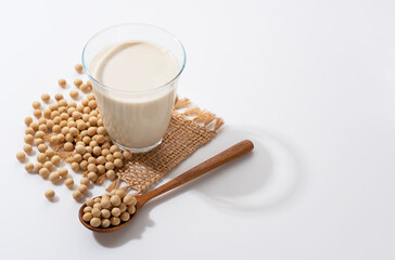 Soy milk, soybeans and a wooden spoon on a white background