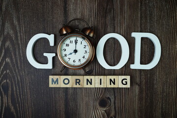 Good Morning alphabet letters with alarm clock on wooden background