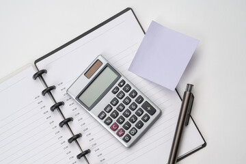 Top view of notebook with pen, sticky note and calculator with white isolated background 
