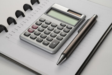 close up of notebook with pen and calculator on white flat surface
