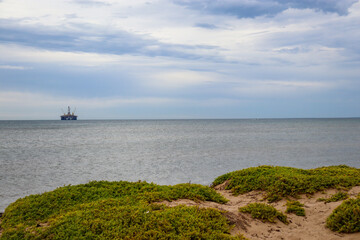 oil rig in the sea with seashore in foreground