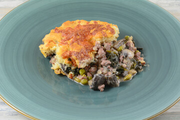 Serving of beef and vegetable casserole with cheese biscuit crust on blue dinner plate
