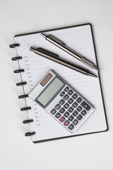 Top view of notebook with pen and calculator with white isolated background 