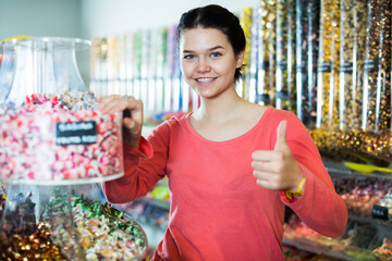 Happy brunette girl buying candies at shop