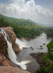 Naklejka na ściany i meble waterfall with cloudy sky and green forests of western ghat range