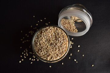 Top View Closeup Urad Dal,mash ki Dal ,White Gram in a Open Transparent Glass jar On isolated Black Background