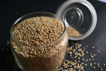Sesame Seeds in a Open Transparent Glass jar Top View Closeup  On isolated Black Background