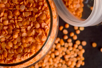 Red Lentils in a Open Transparent Glass jar Top View Closeup  On isolated Black Background