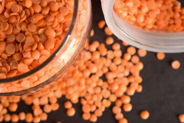 Red Lentils in a Open Transparent Glass jar Top View Closeup  On isolated Black Background