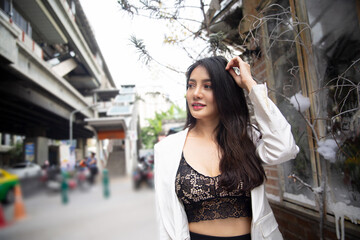 portrait of a woman with long hair in white suit standing on street. 