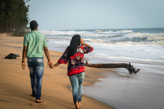Couple walking on sandy beach with holding each others hand and soaking up the natural sea view image is taken at kochi kerala india showing the love and affection of the couple in the true nature.