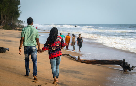 Couple walking on sandy beach with holding each others hand and soaking up the natural sea view image is taken at kochi kerala india showing the love and affection of the couple in the true nature.