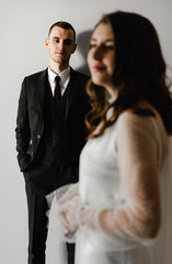 husband looks at his wife. groom smiling looking at the bride standing in the foreground. portrait of people. wedding day.