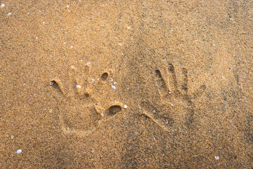 Couple hand prints on yellow sandy beach showing love for each other and the nature