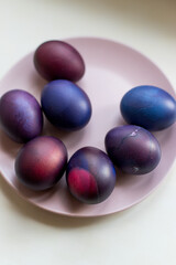 Painted blue and purple Easter eggs on a textured background. Easter eggs on a plate.