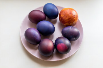 Fototapeta na wymiar Painted blue and purple Easter eggs on a textured background. Easter eggs on a plate.