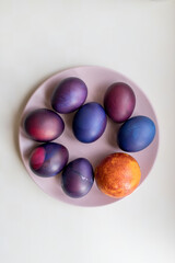 Painted blue and purple Easter eggs on a textured background. Easter eggs on a plate.