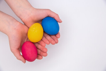 Children's hands are holding colored Easter eggs.