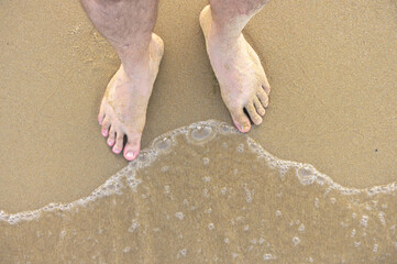 Men feet on the sand