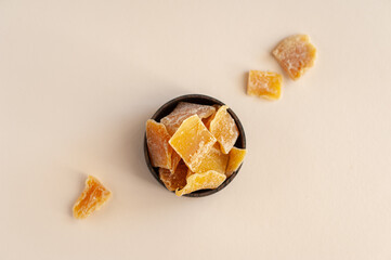 Candied mango. Pieces of Jerky mango in a wooden plate on a beige background. Selective focus....