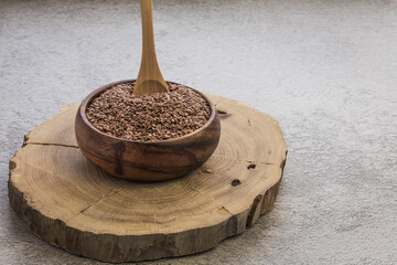 Flax seeds in a wooden bowl on a concrete background, a dietary cereal ingredient for granola that...