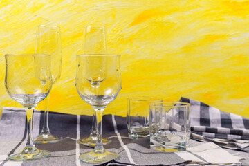 Set of glasses for different alcoholic drinks on yellow background. Empty clear glassware.