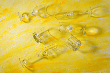 Empty drinking glasses on a concrete yellow background in the rays of the sun. top view