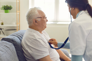 Obraz premium Doctor listening to the heart and breathing of an older man through a stethoscope on his chest.
