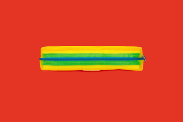 yellow pencil case on a red surface