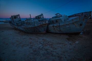 rusty old ships standing in the ice of a frozen lake at sunset