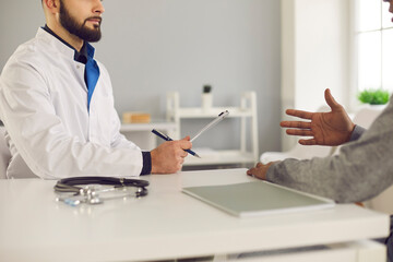 Patient talking to therapeutist about his symptoms and asking for health advice during medical interview at the doctor's office. Concept of professional consultation at the clinic or hospital