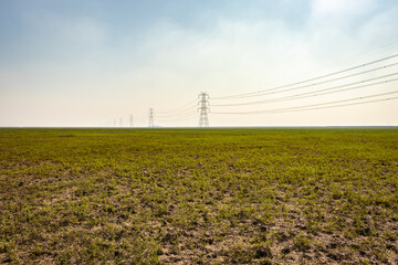 electricity pole with high tension power transmission cable in green fields of countryside area